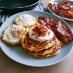 Hartige keto pannenkoekjes met gebakken ei, bacon en romige topping op een ontbijtbord.